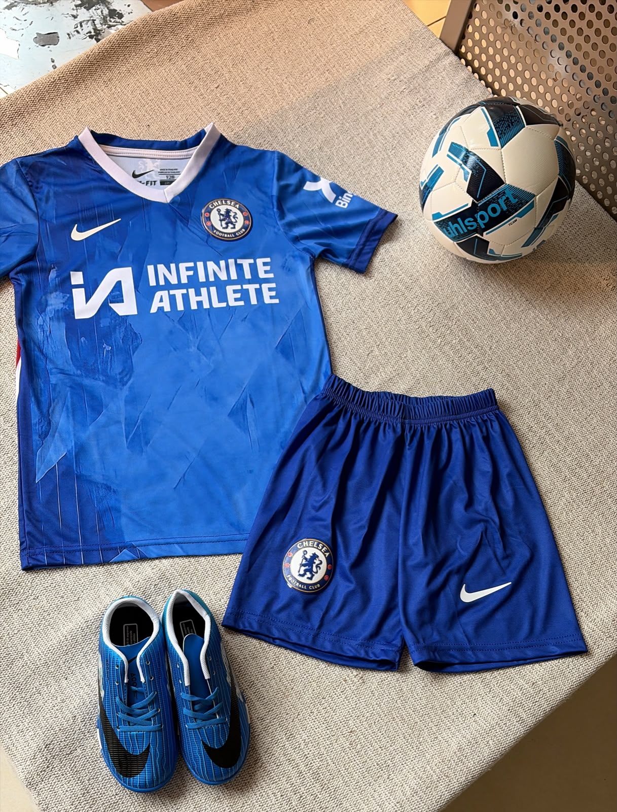 Chelsea FC kids football kit royal blue Nike jersey Infinite Athlete sponsor and blue shorts flat lay