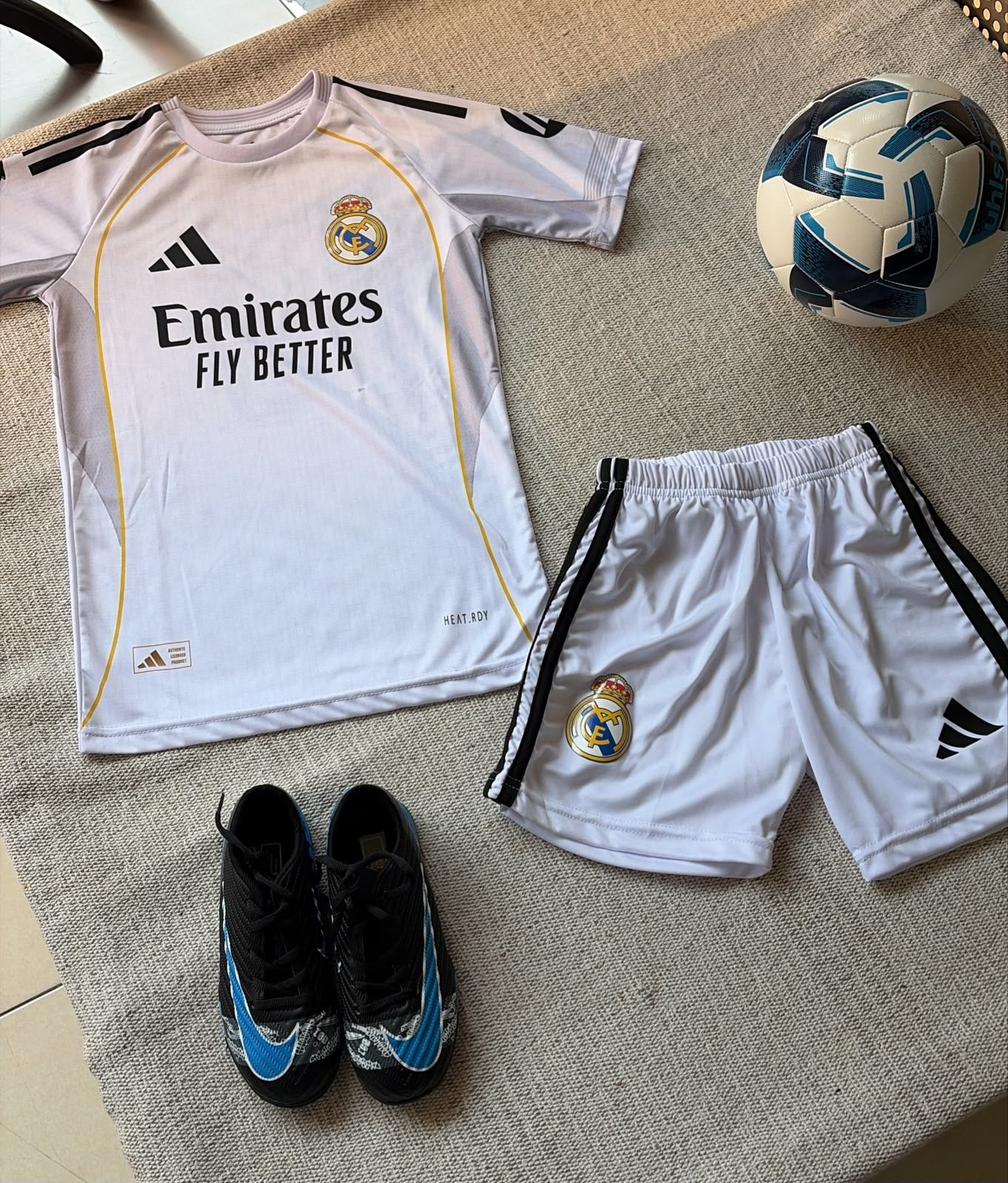 Real Madrid kids home football kit white Adidas jersey Emirates sponsor and white shorts flat lay