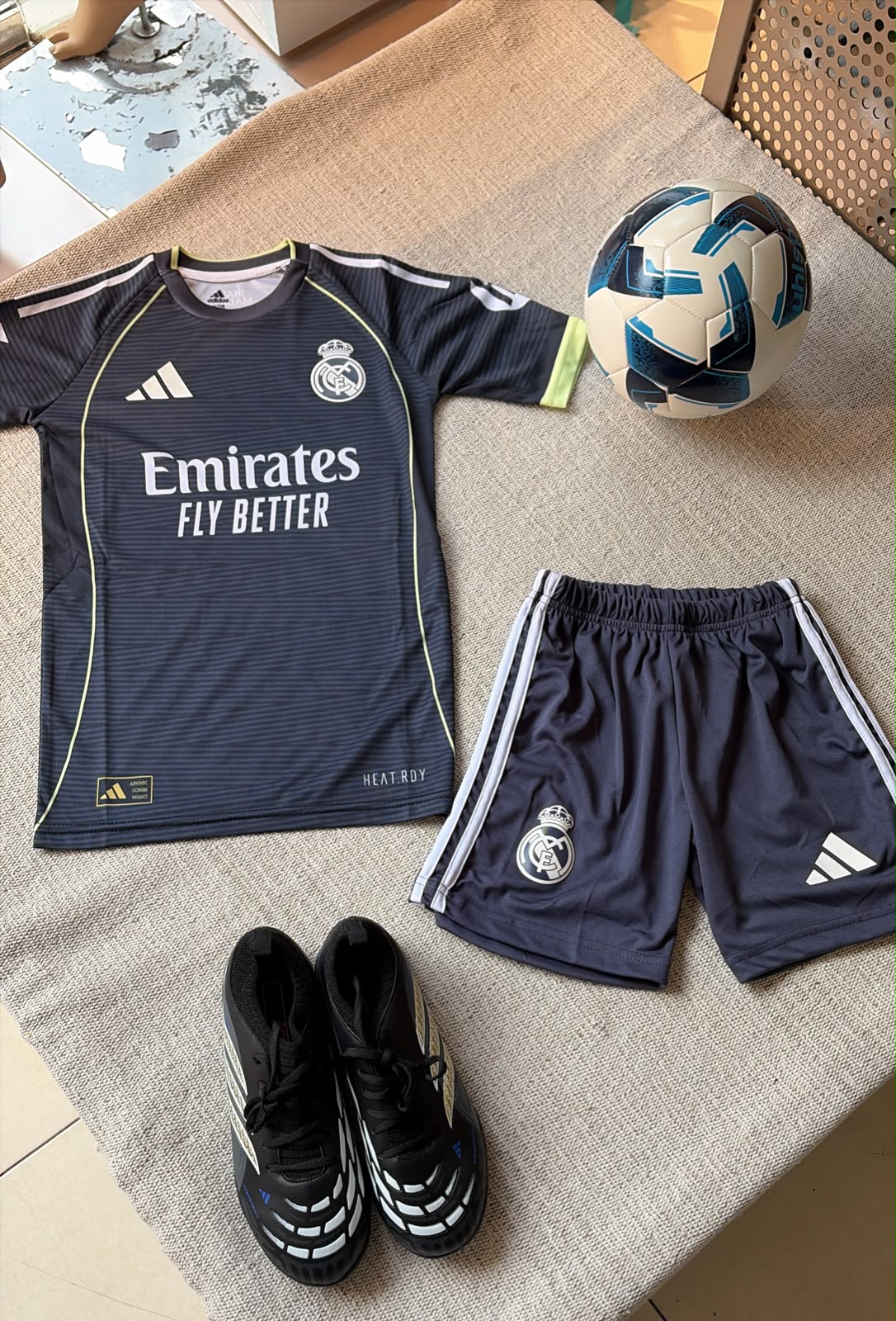 Real Madrid kids away football kit dark navy Adidas jersey Emirates sponsor and dark navy shorts flat lay
