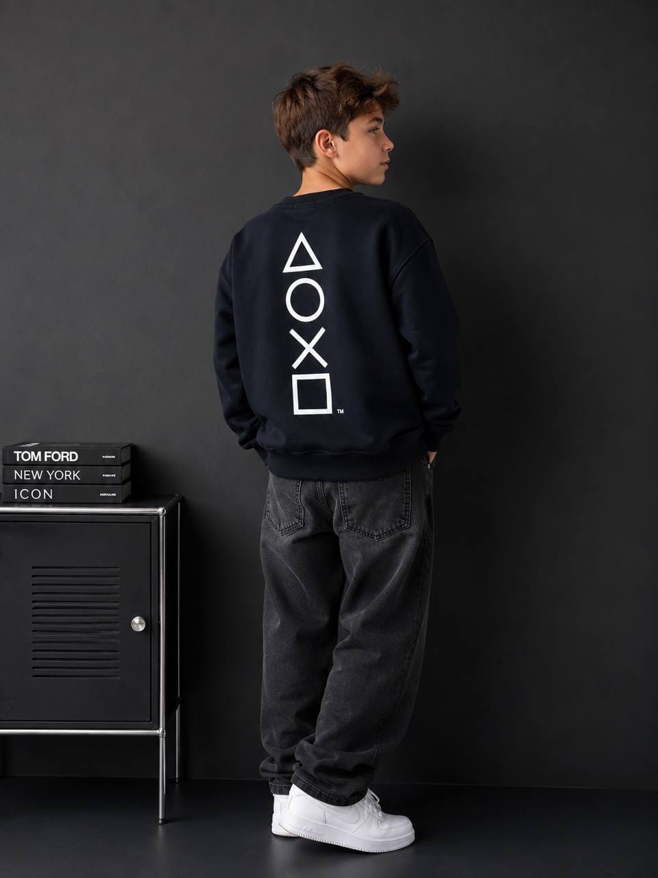 Boy wearing navy PlayStation symbols graphic sweatshirt