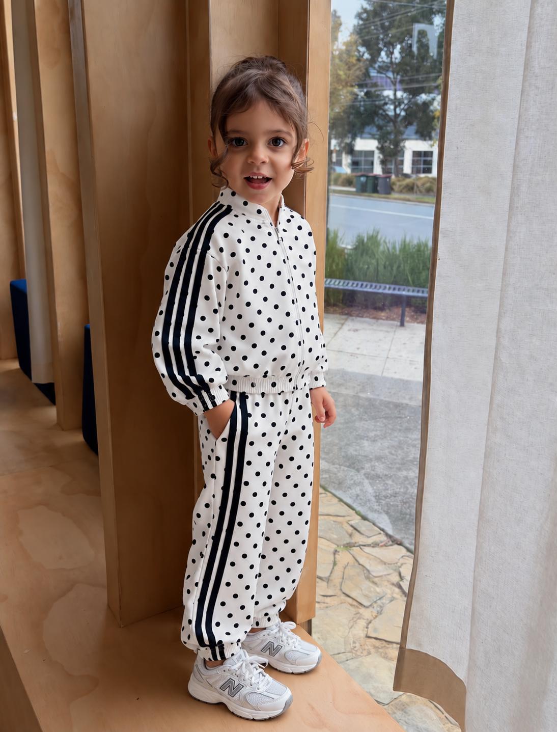 Girls' white tracksuit with black polka dots and black side stripes, featuring a zip-front jacket and matching joggers