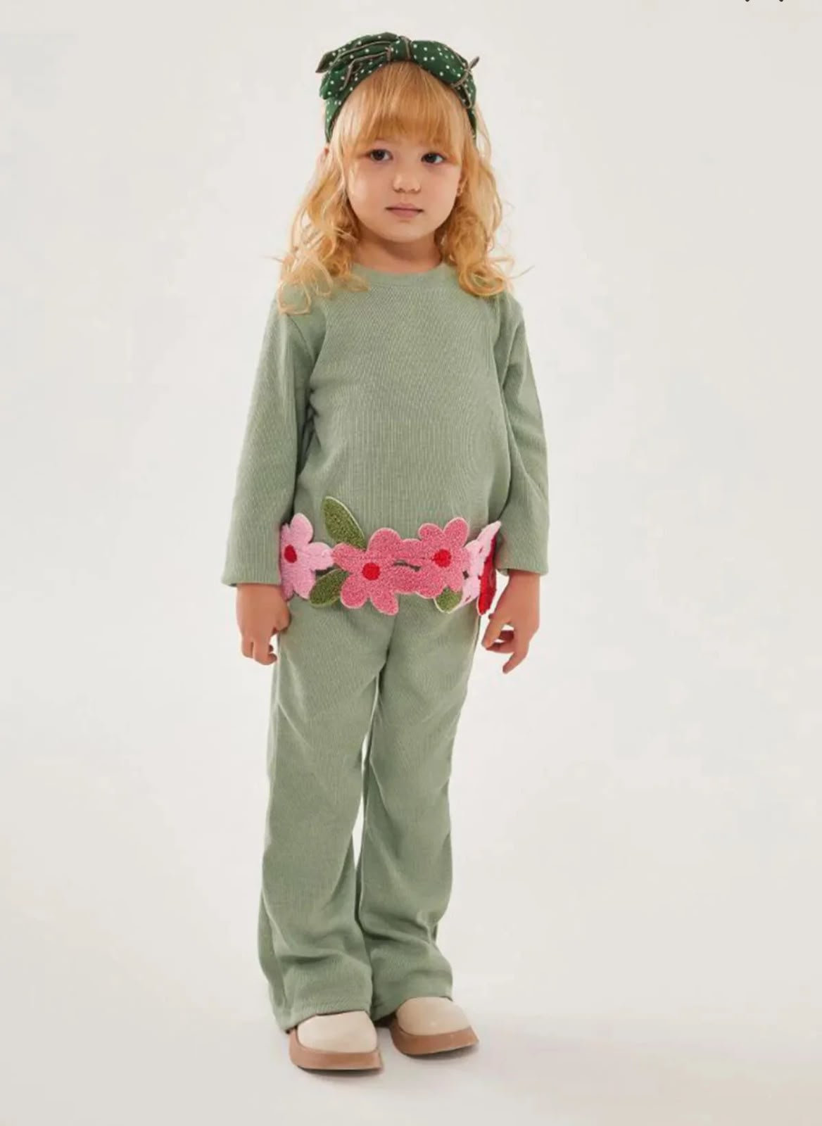 Girl wearing a sage green long-sleeve top with pink flower appliqués and matching green pants
