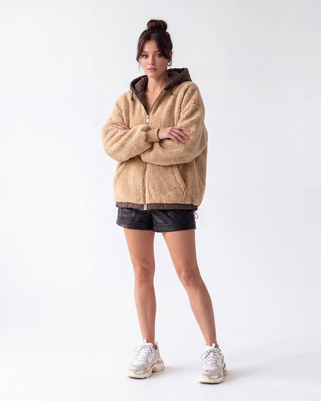 Woman wearing a beige hooded teddy-textured jacket with dark trim