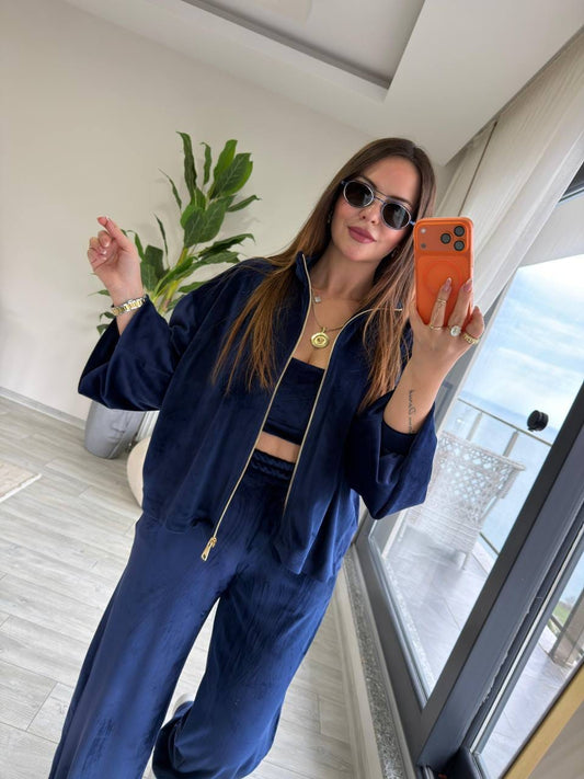 Woman wearing a navy zip-up jacket with a gold-tone zipper and matching wide-leg pants.