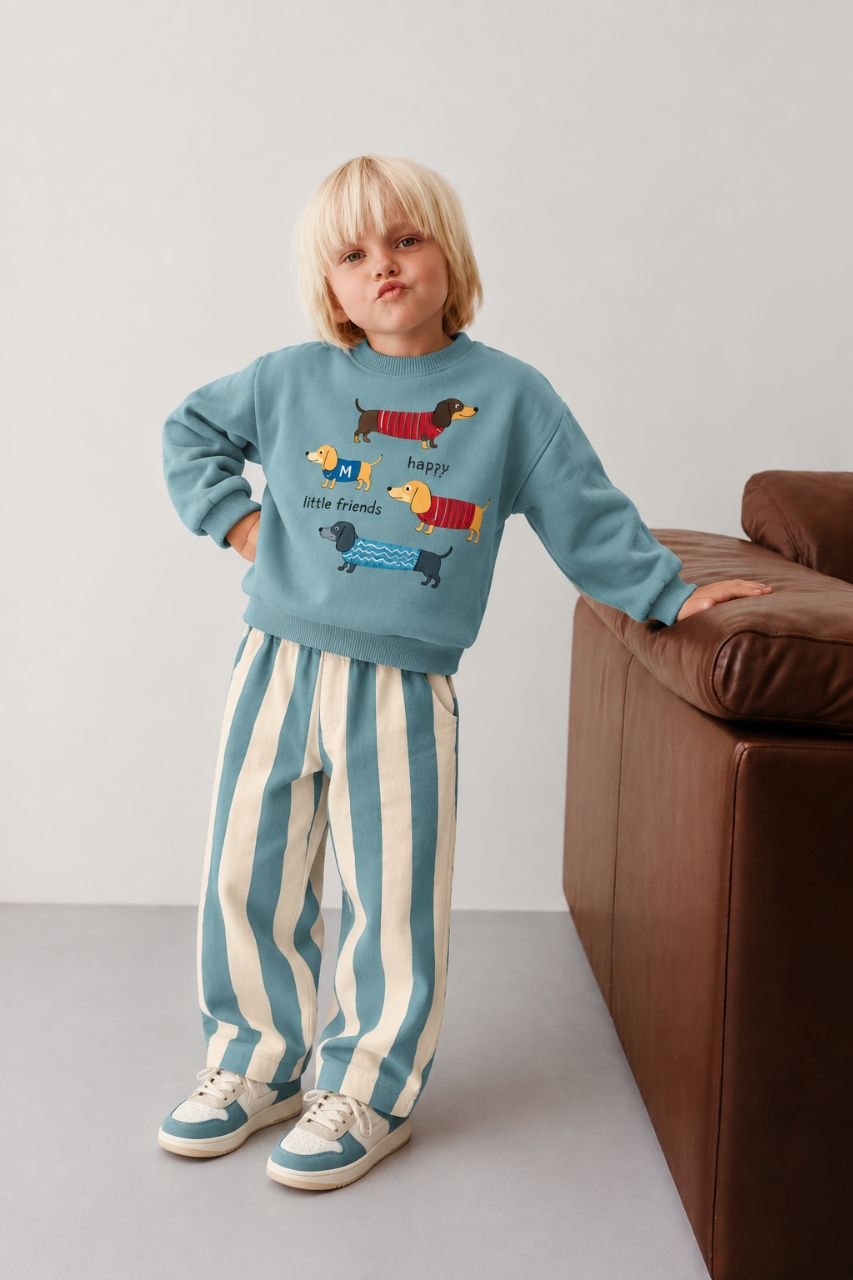 Child wearing a blue sweatshirt with colorful dog graphics and blue-and-cream vertically striped pants.