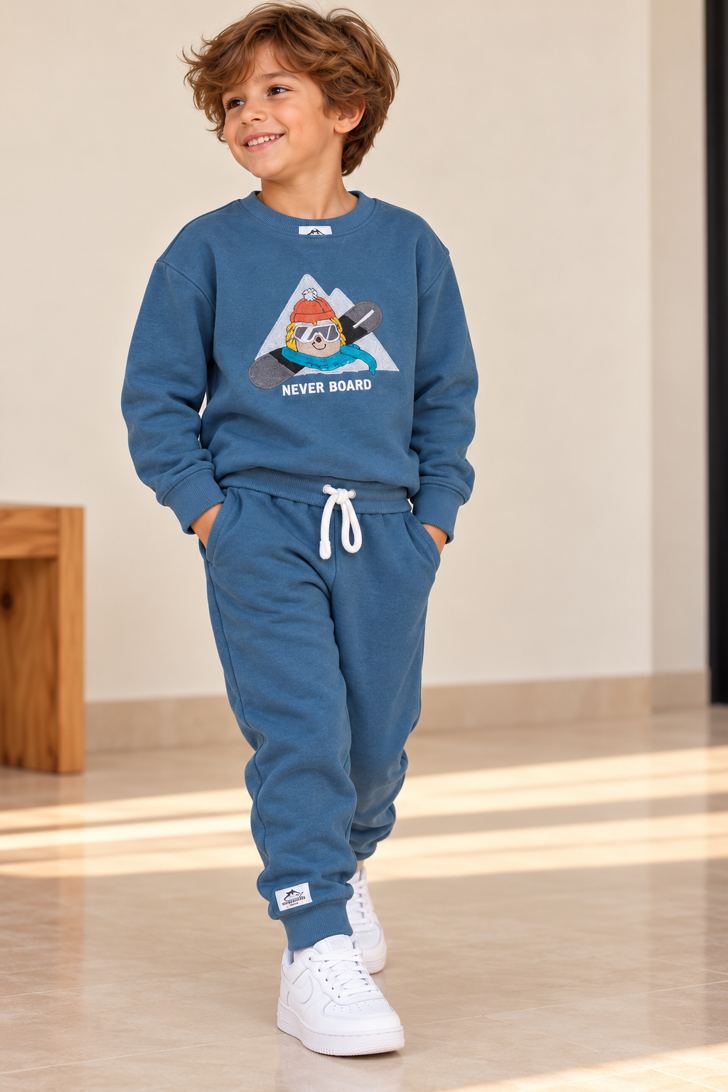 Boy wearing a blue Never Board graphic sweatshirt and matching blue drawstring joggers