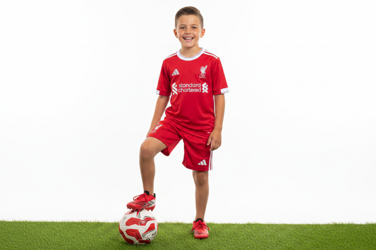 Boy wearing Liverpool FC kids home football kit red jersey and red shorts