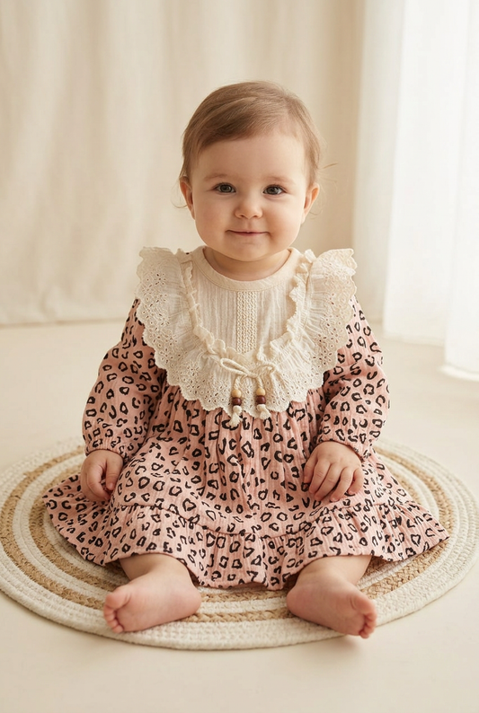 One-year-old girl wearing the pink dress with ivory lace details